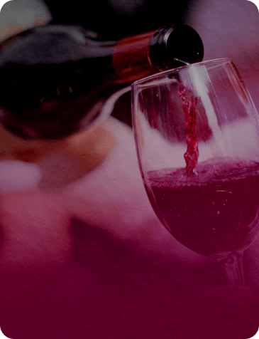 red wine being poured into a glass with a magenta tint